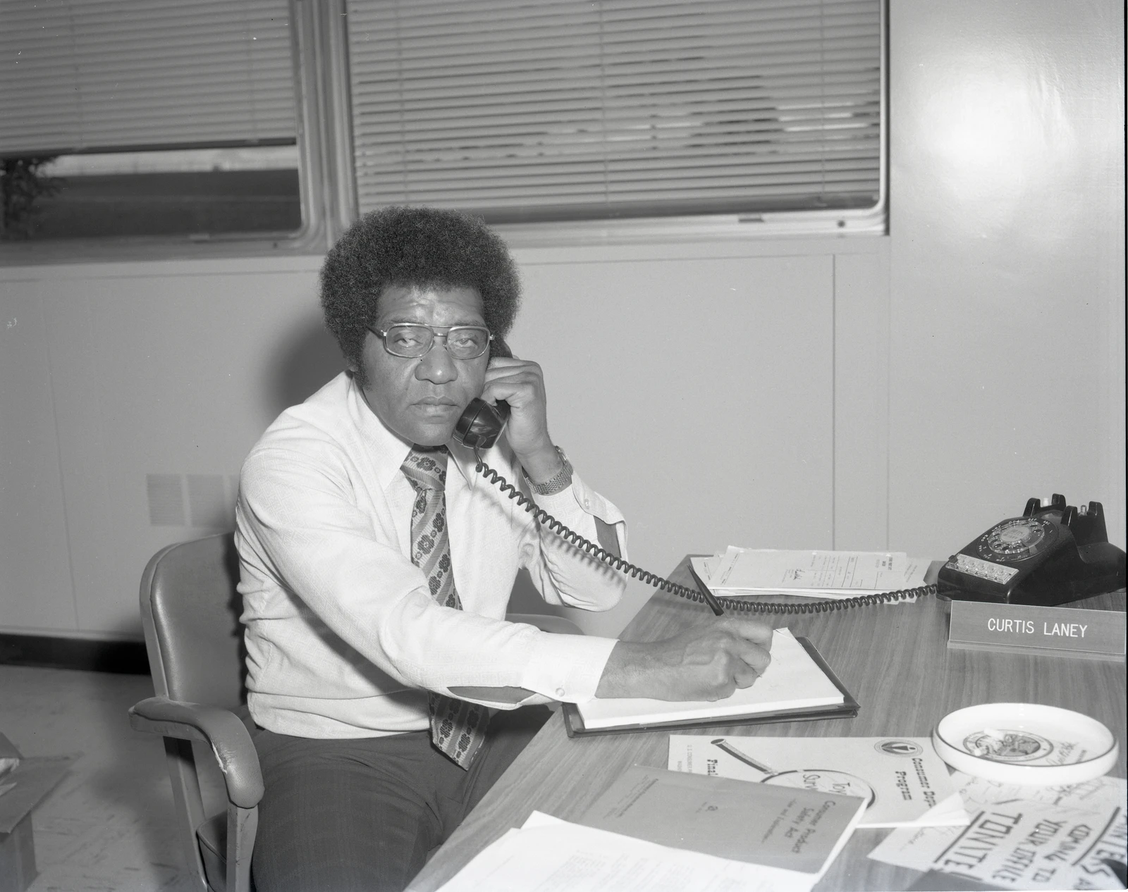 Curtis Laney, Consumer Protection Office employee, on a rotary phone at his desk.
