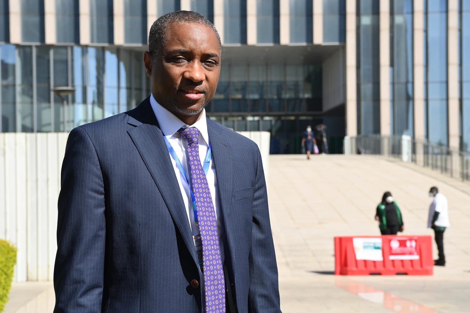 Abdou Salam Ndiath standing outdoors in front of a modern building.