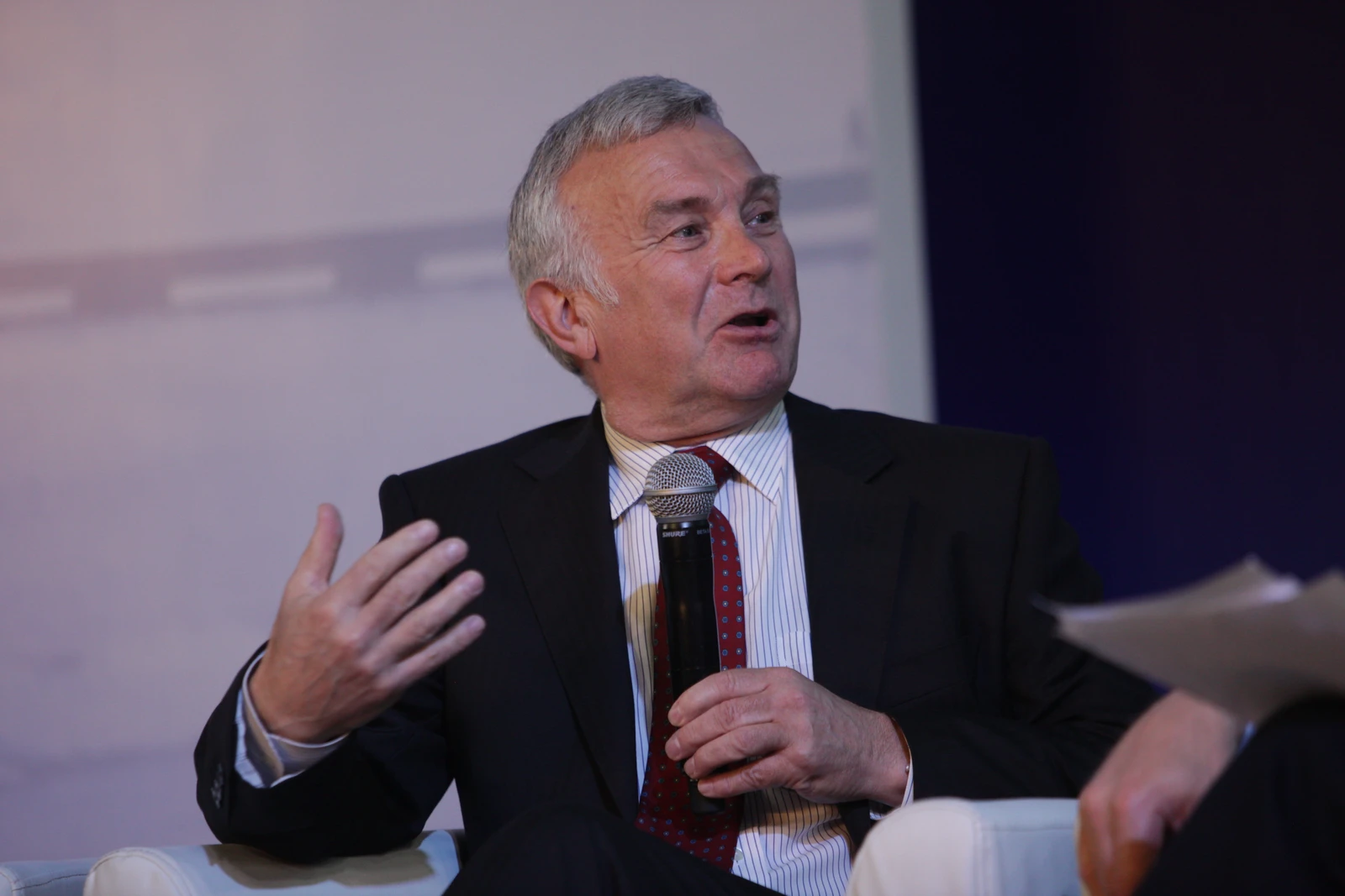 John Walker, Chairman of Oxford Economics, speaking into a microphone at an event.