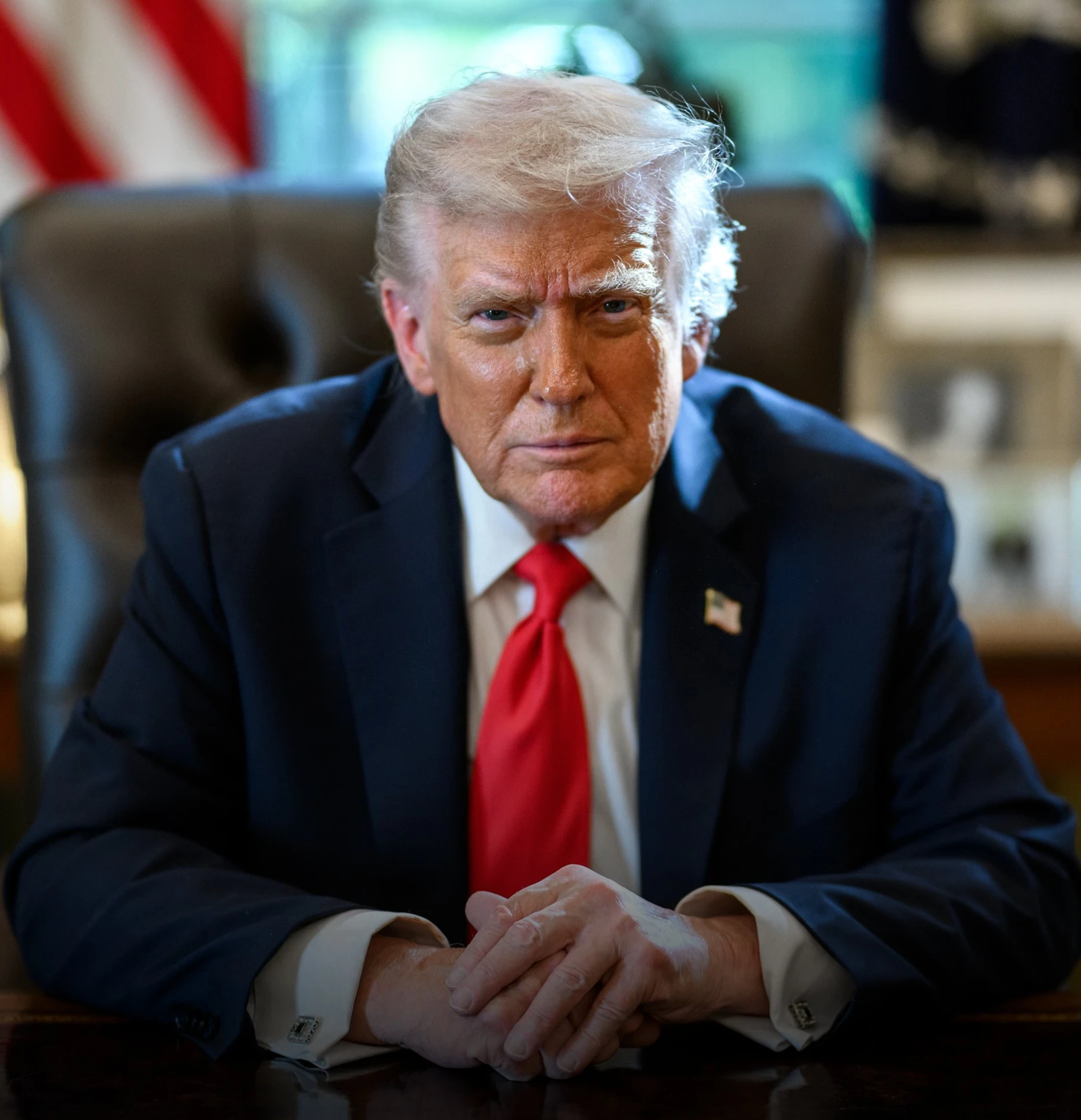 Donald Trump, former U.S. President, sitting at a desk.
