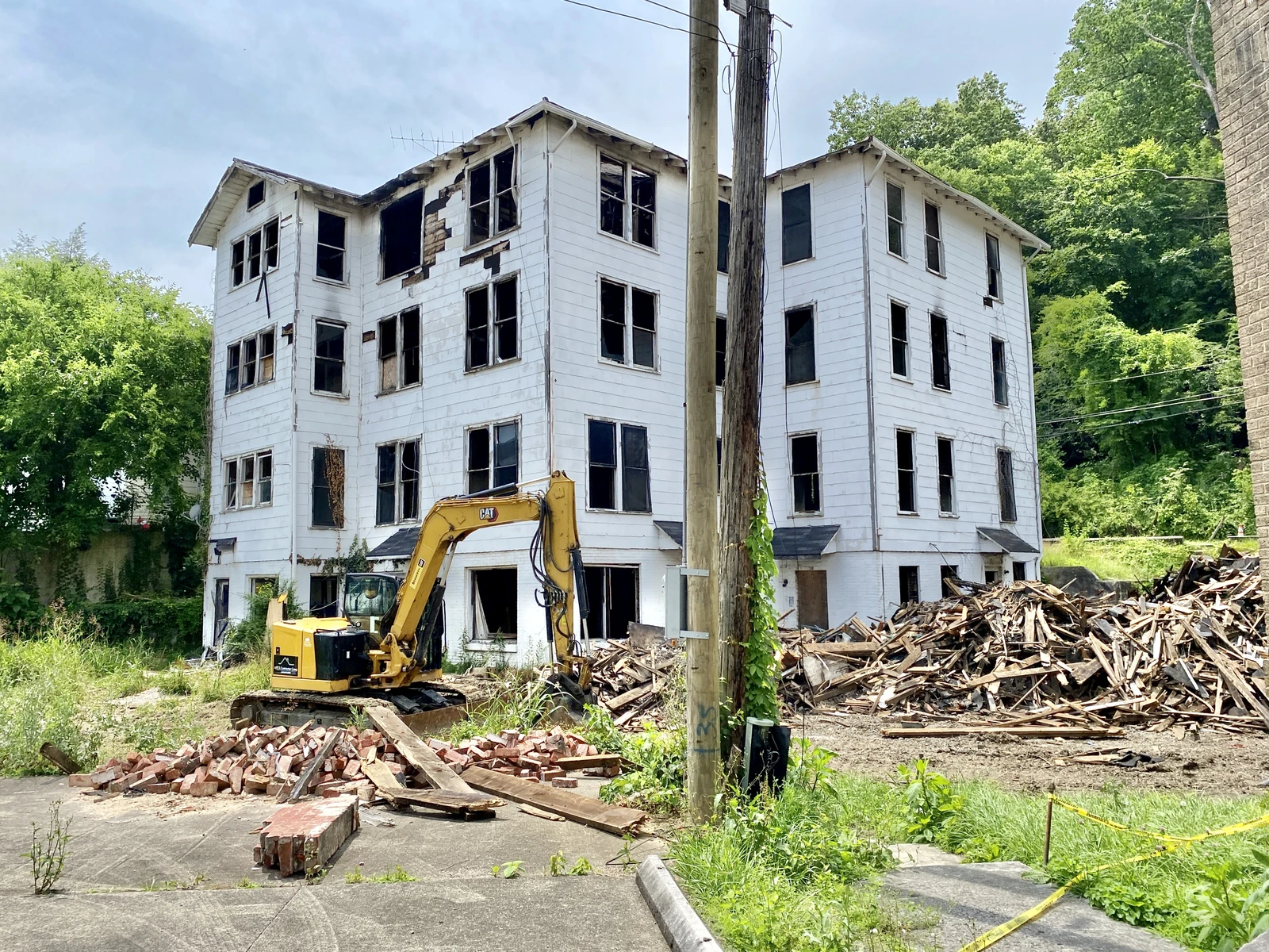 Old apartment building in disrepair with an excavator next to piles of debris in Middlesboro, Kentucky.
