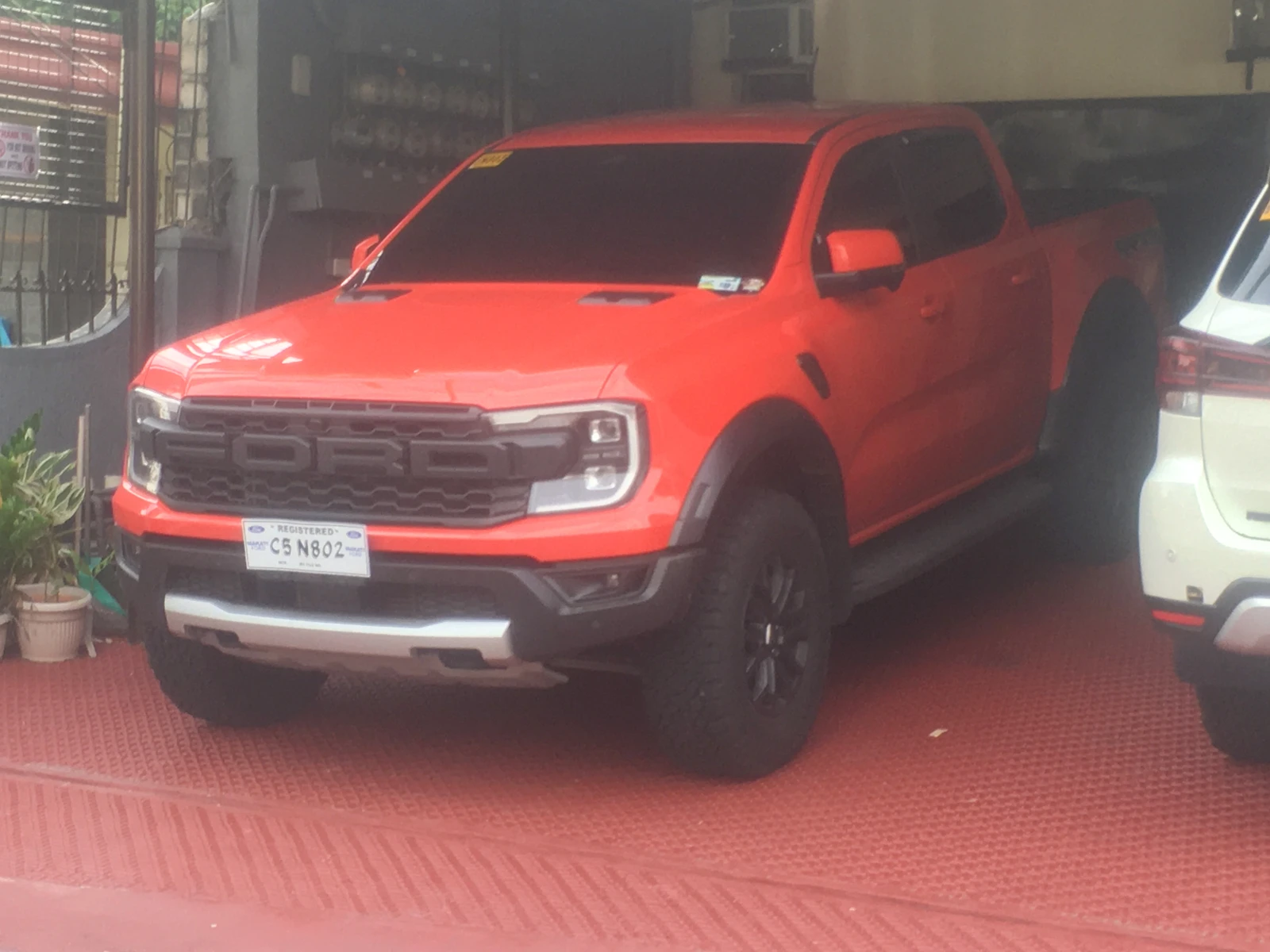 Orange Ford Ranger Raptor pickup truck parked inside a garage.