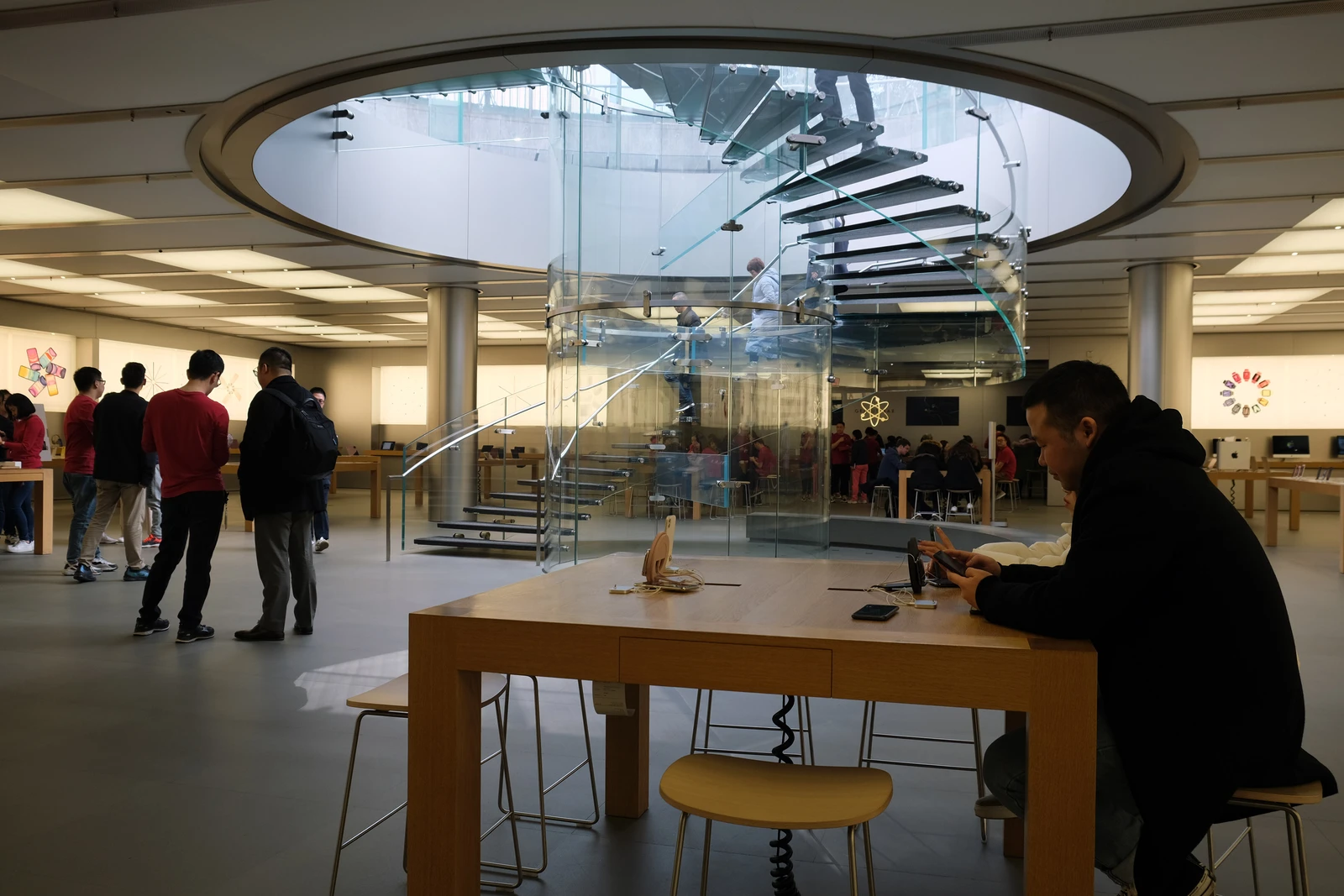Customers browsing Apple products inside a modern Apple Store in Shanghai.