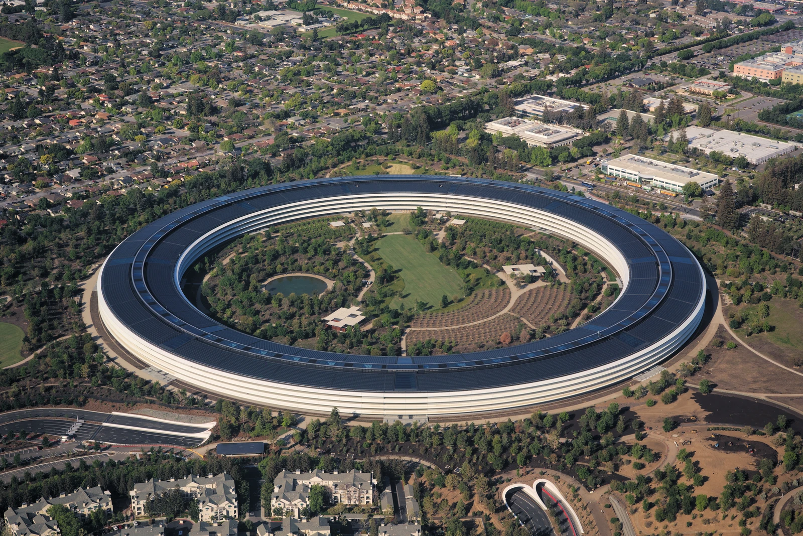 Aerial view of Apple Park campus, a large circular building surrounded by greenery.