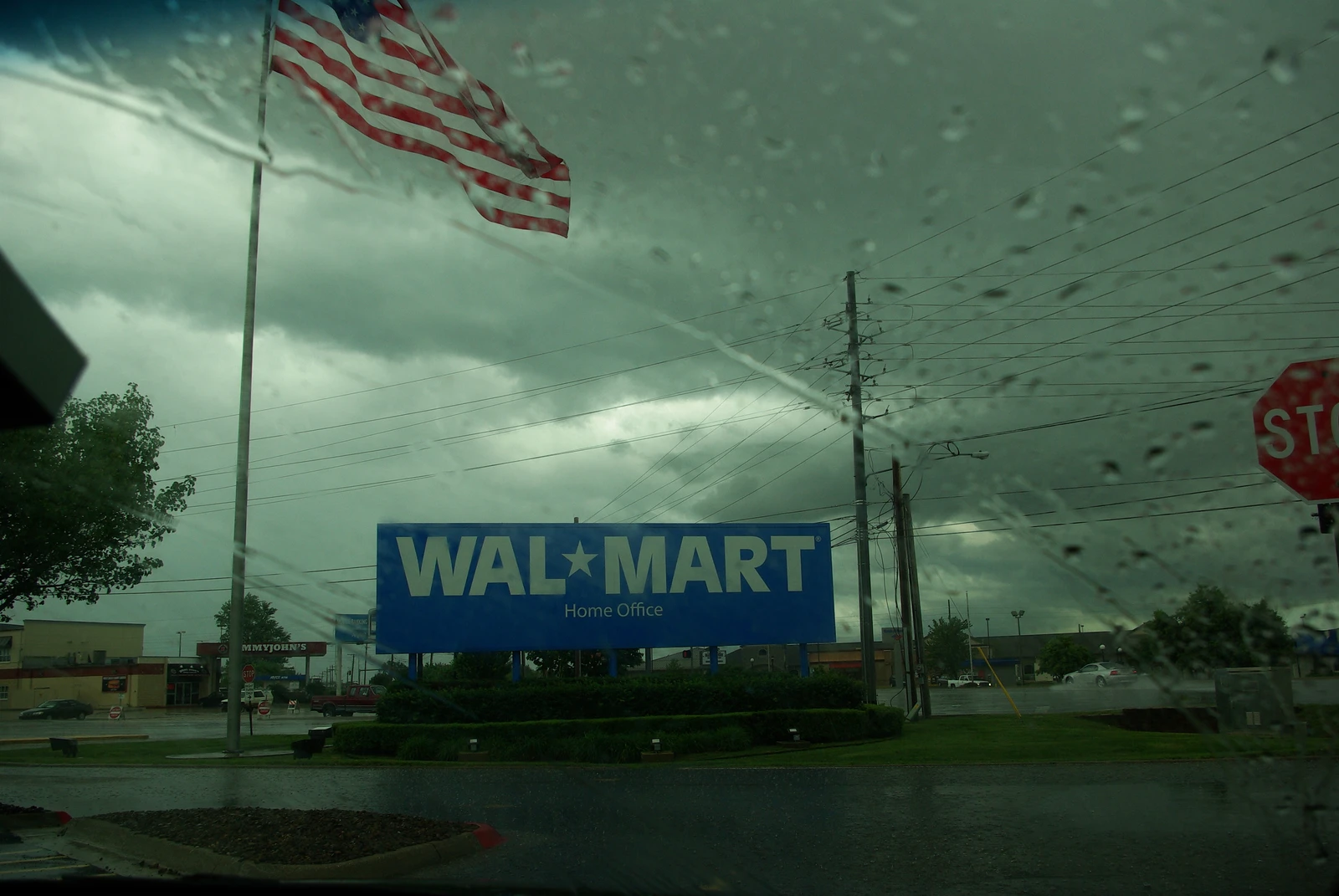 Walmart Home Office sign in Bentonville, Arkansas, with American flag and rainy weather.