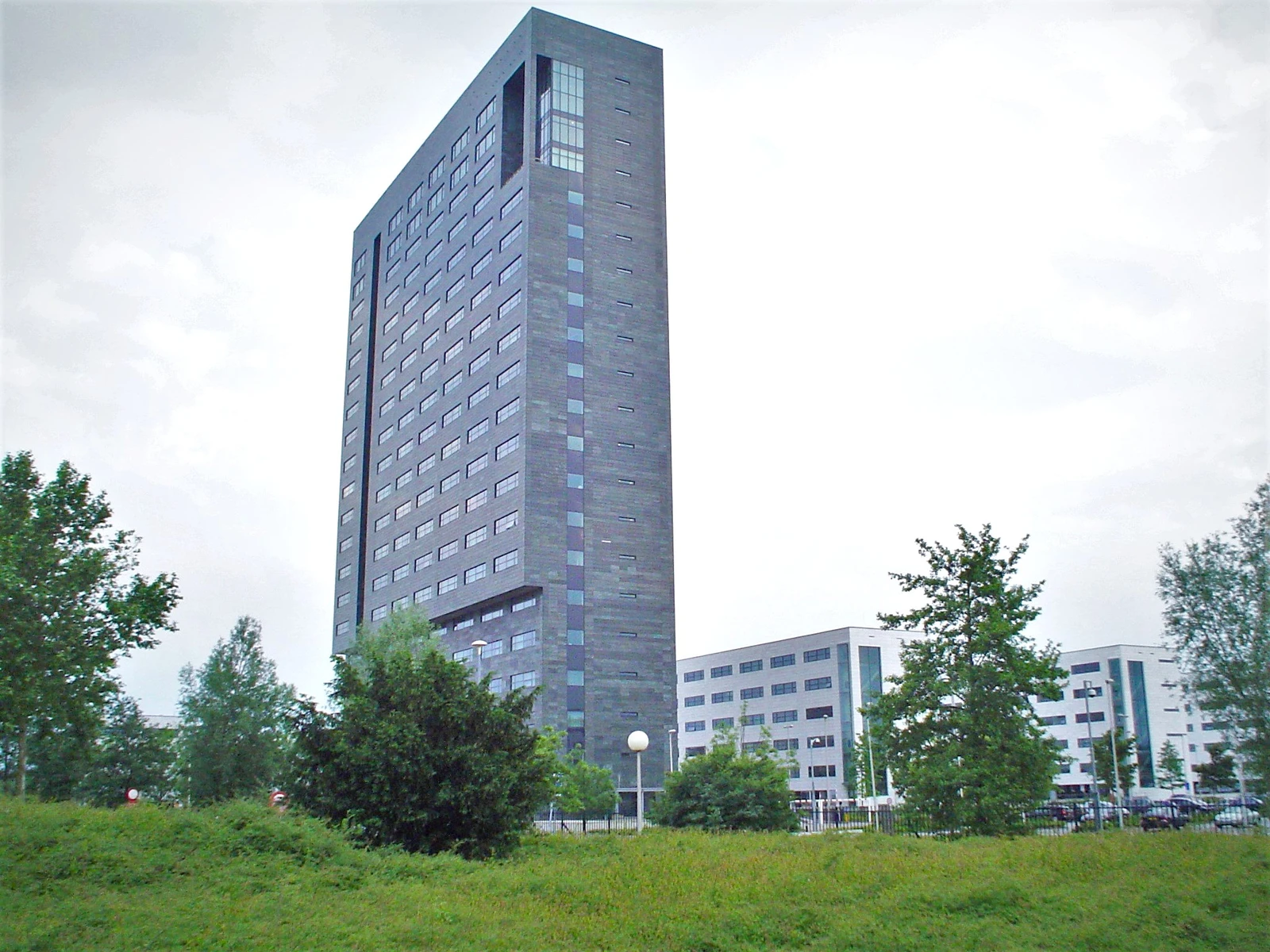 ASML headquarters building in Veldhoven, Netherlands, with surrounding greenery under a cloudy sky.