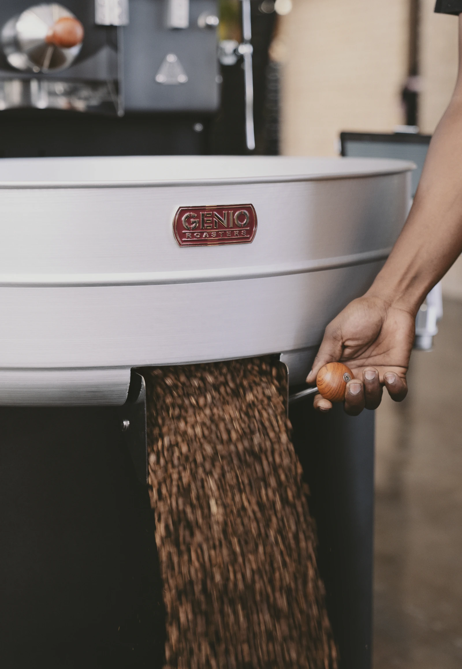 Roasted coffee beans pouring from a large commercial coffee roasting machine.