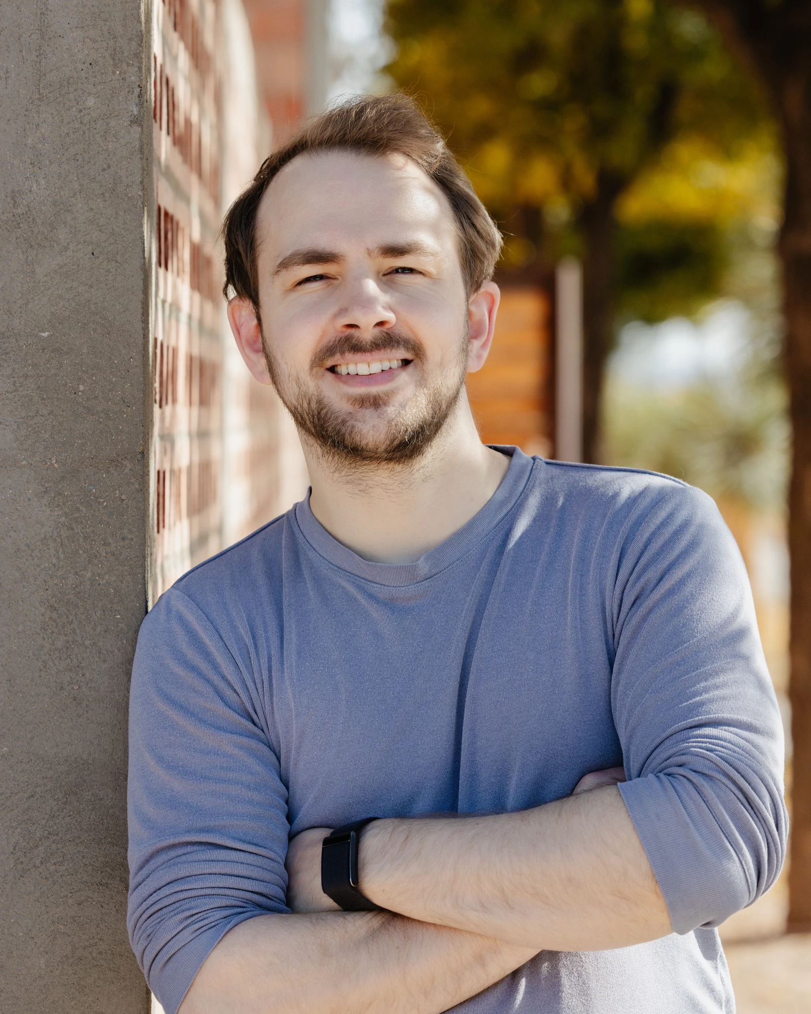 Devin Finzer, co-founder and CEO of OpenSea, standing with arms crossed next to a brick wall.