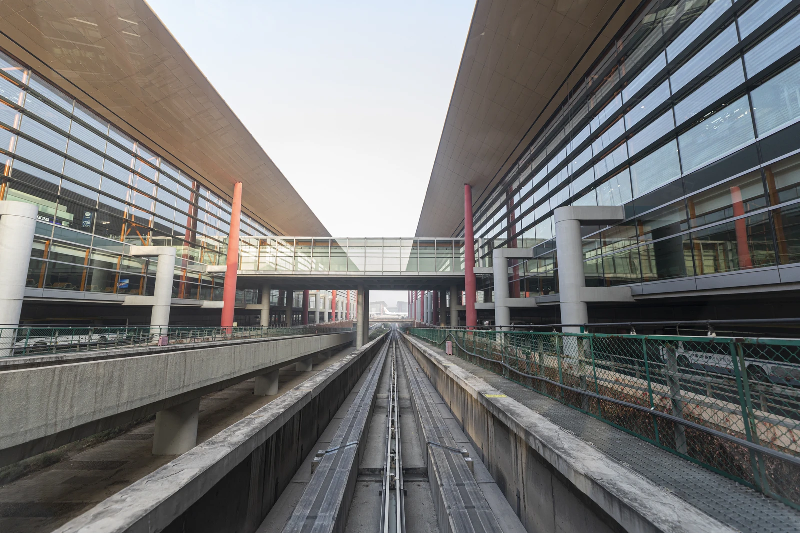 Exterior of Beijing Capital International Airport's Terminal 3 showing airport buildings and tracks.