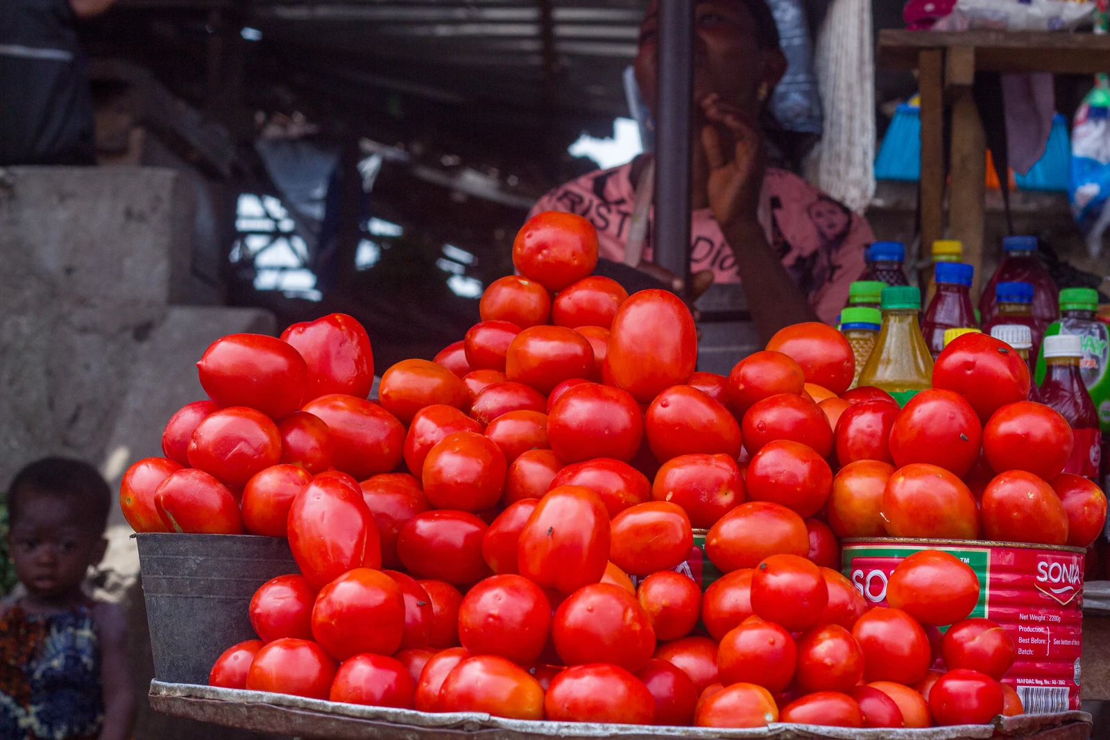 Heaps of fresh red tomatoes are displayed for sale at a market stall.
