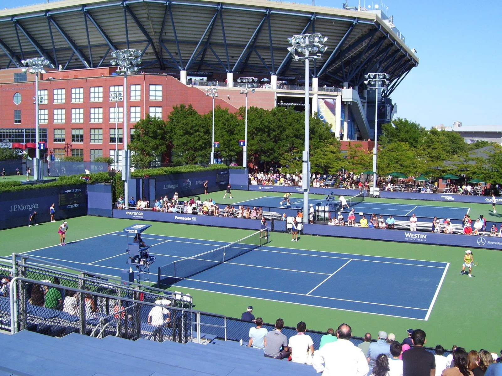 Multiple tennis courts and a large stadium structure with spectators visible at the National Tennis Center.