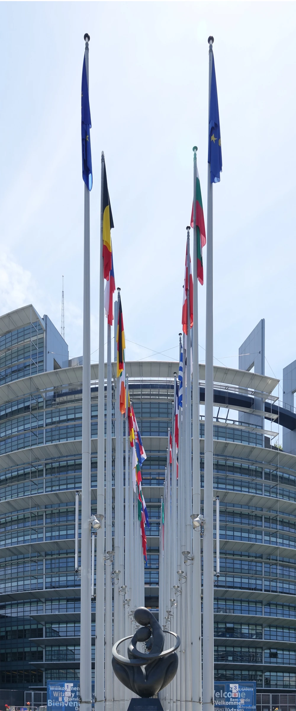 Exterior of the European Parliament in Strasbourg with European Union and national flags flying.