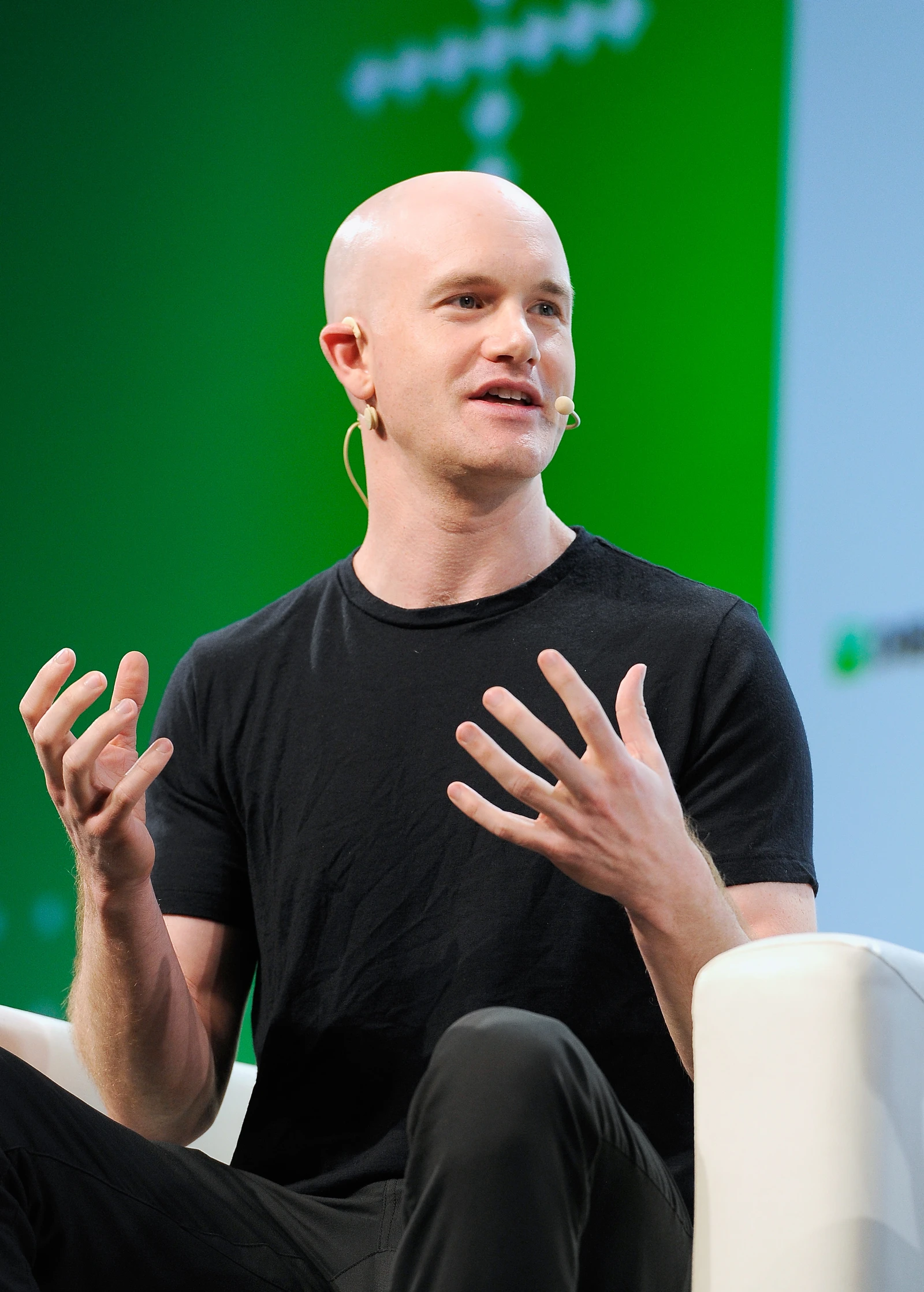 Brian Armstrong, CEO of Coinbase, speaking and gesturing with his hands at a conference.