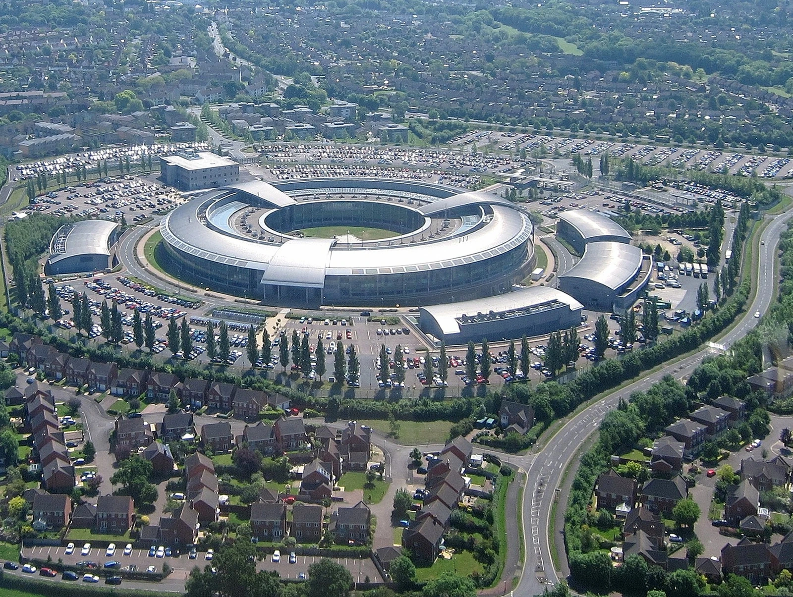Aerial view of the GCHQ building, a large circular complex with surrounding car parks.