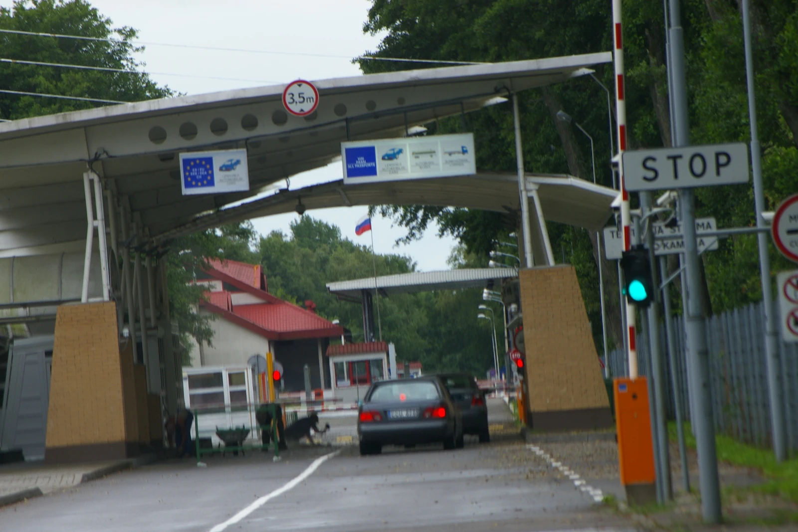 A vehicle border crossing point with a Russian flag and a "STOP" sign.