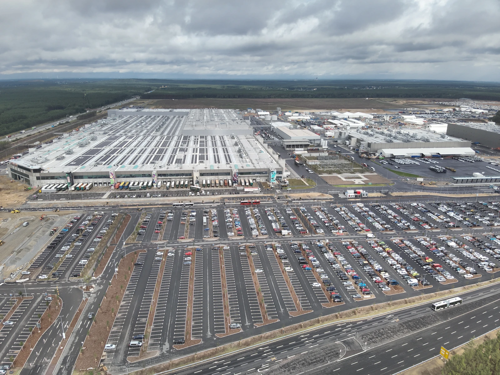 Aerial view of the Tesla Gigafactory production facility and parking lots under cloudy sky.