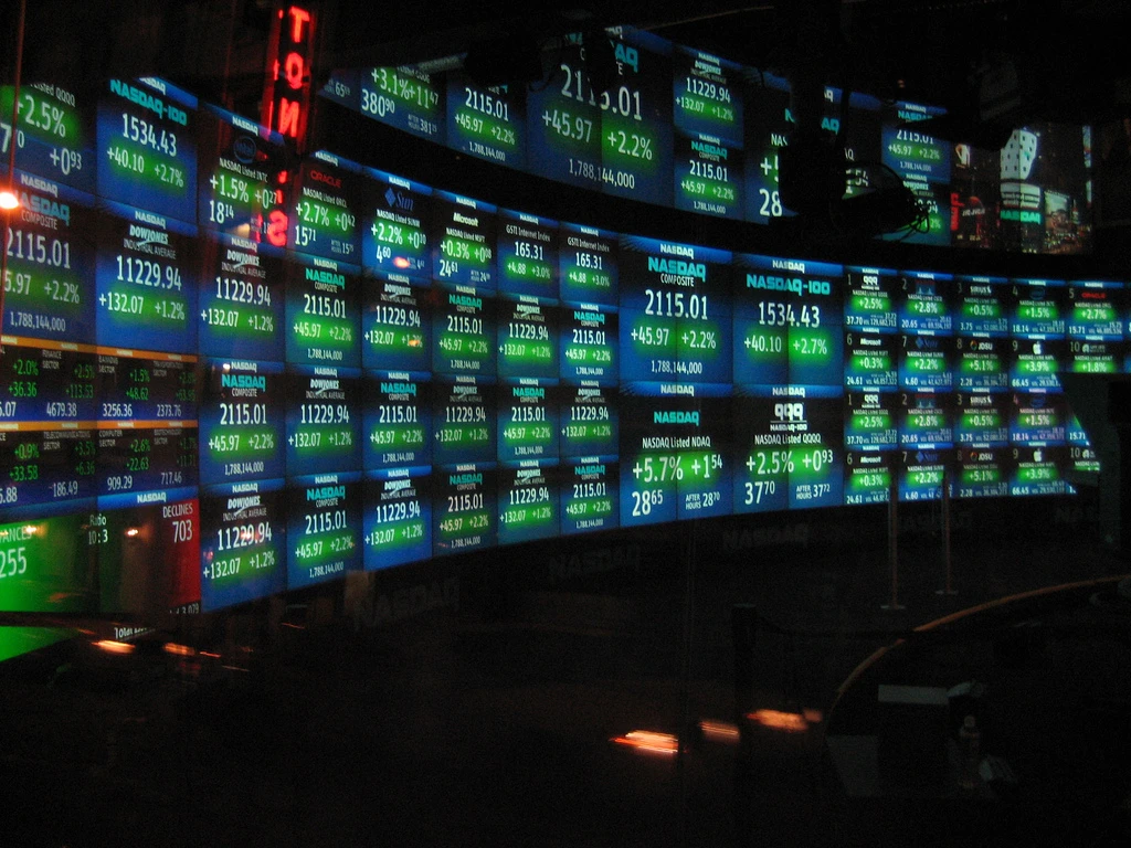 NASDAQ stock market tickers displaying real-time financial data on a large screen.