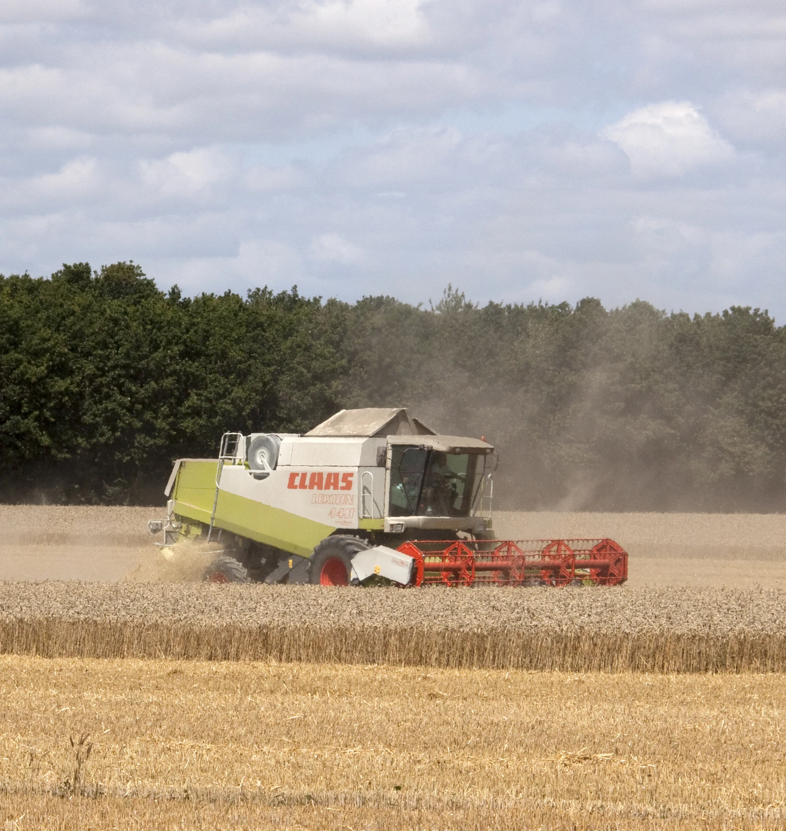 A Claas Lexion 440 combine harvester working in a dry field.