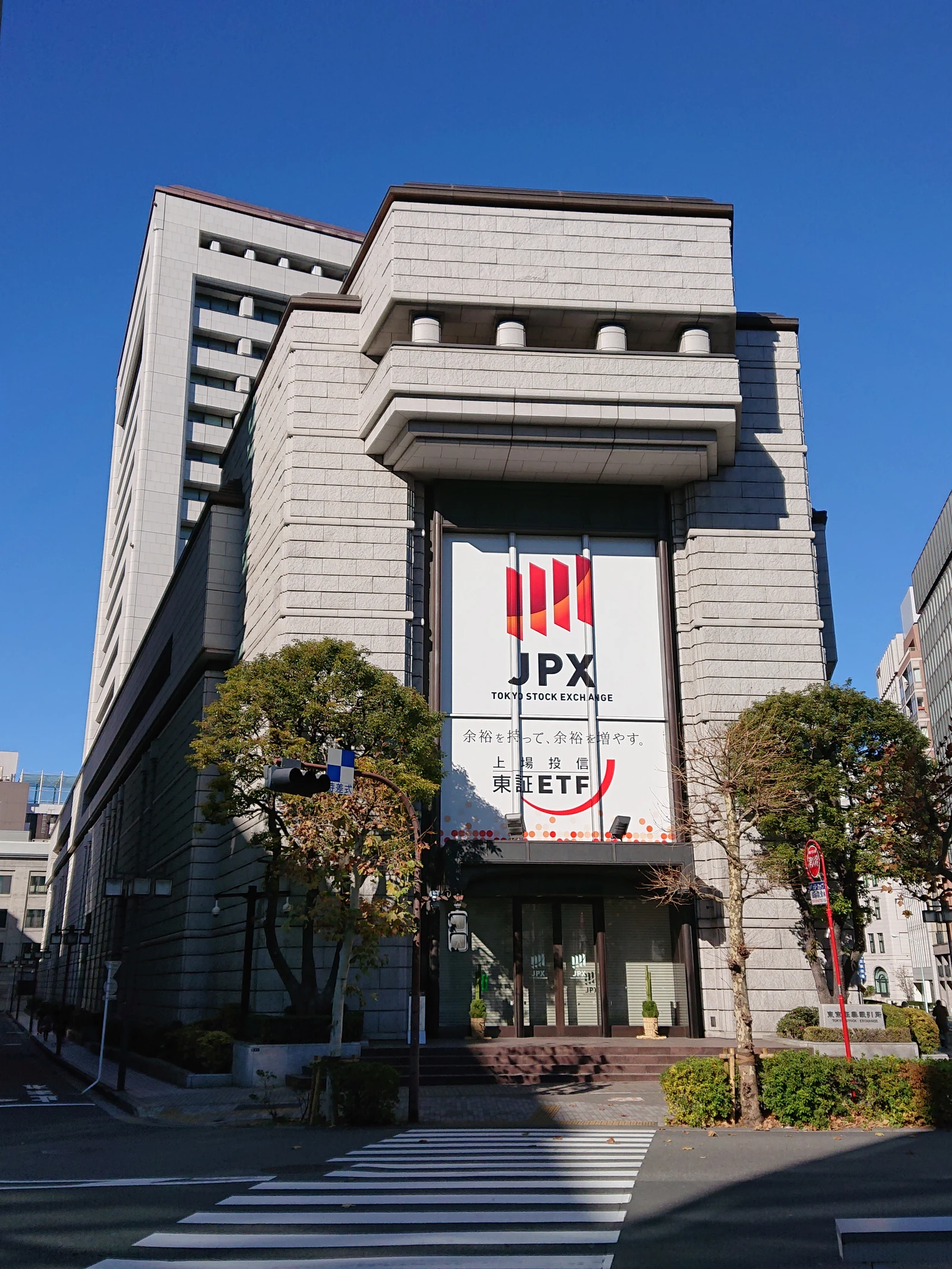 Exterior view of the Tokyo Stock Exchange main building under a clear blue sky.