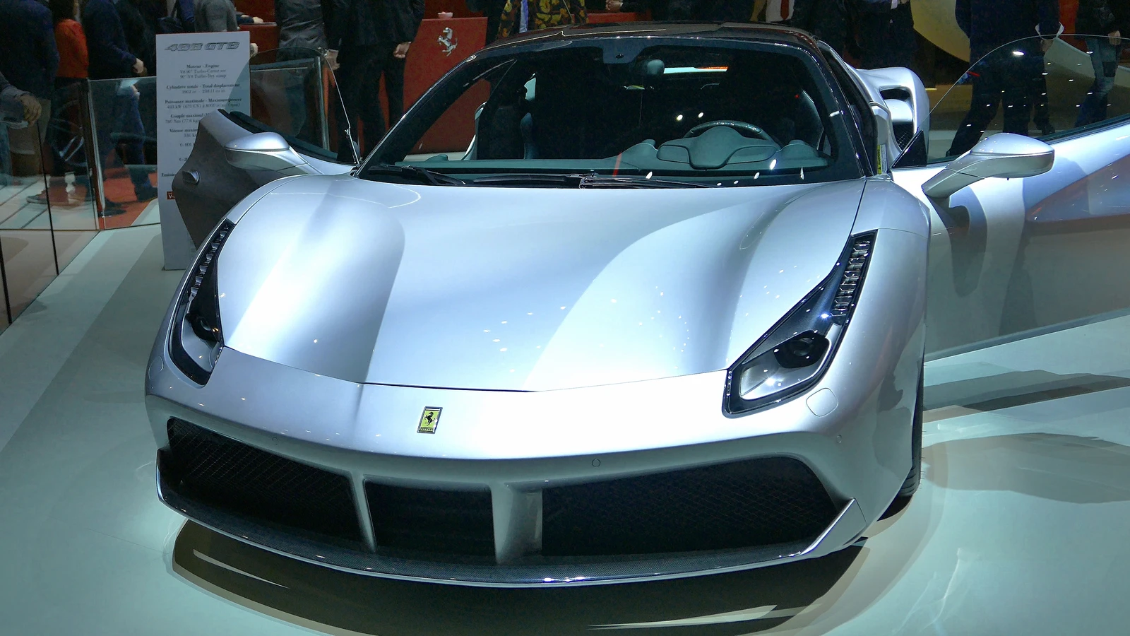 Silver Ferrari luxury sports car on display, with its doors open.