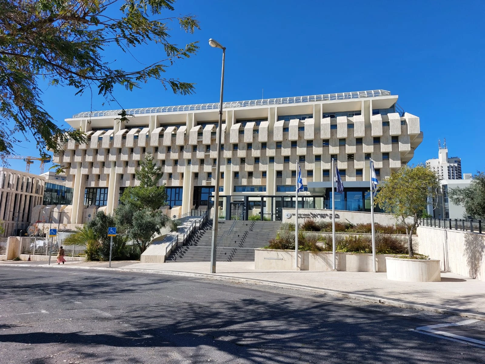 Exterior view of the modern, stone-clad Bank of Israel building under a clear blue sky.
