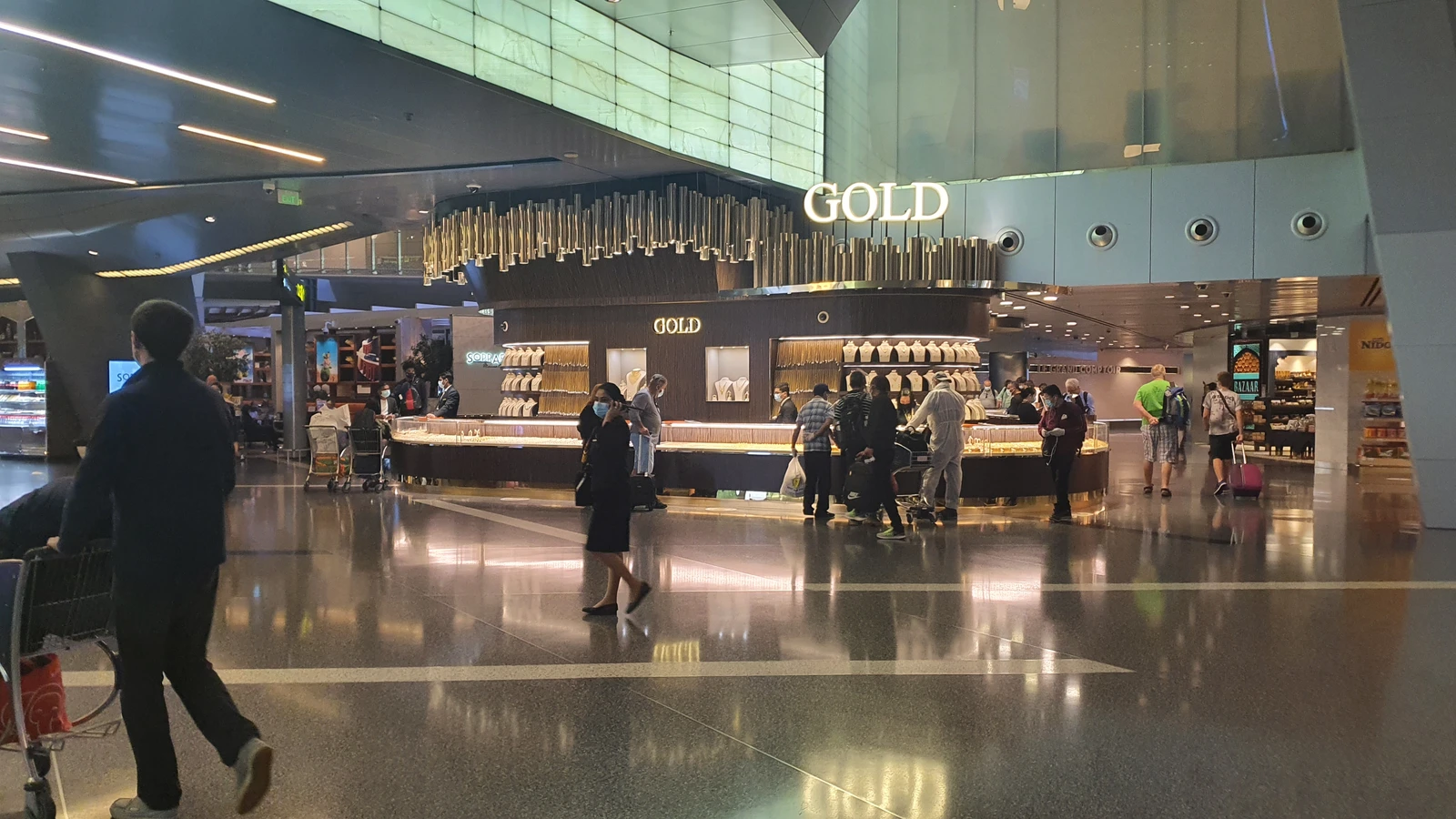 People shopping for gold jewelry inside a duty-free shop at an airport.
