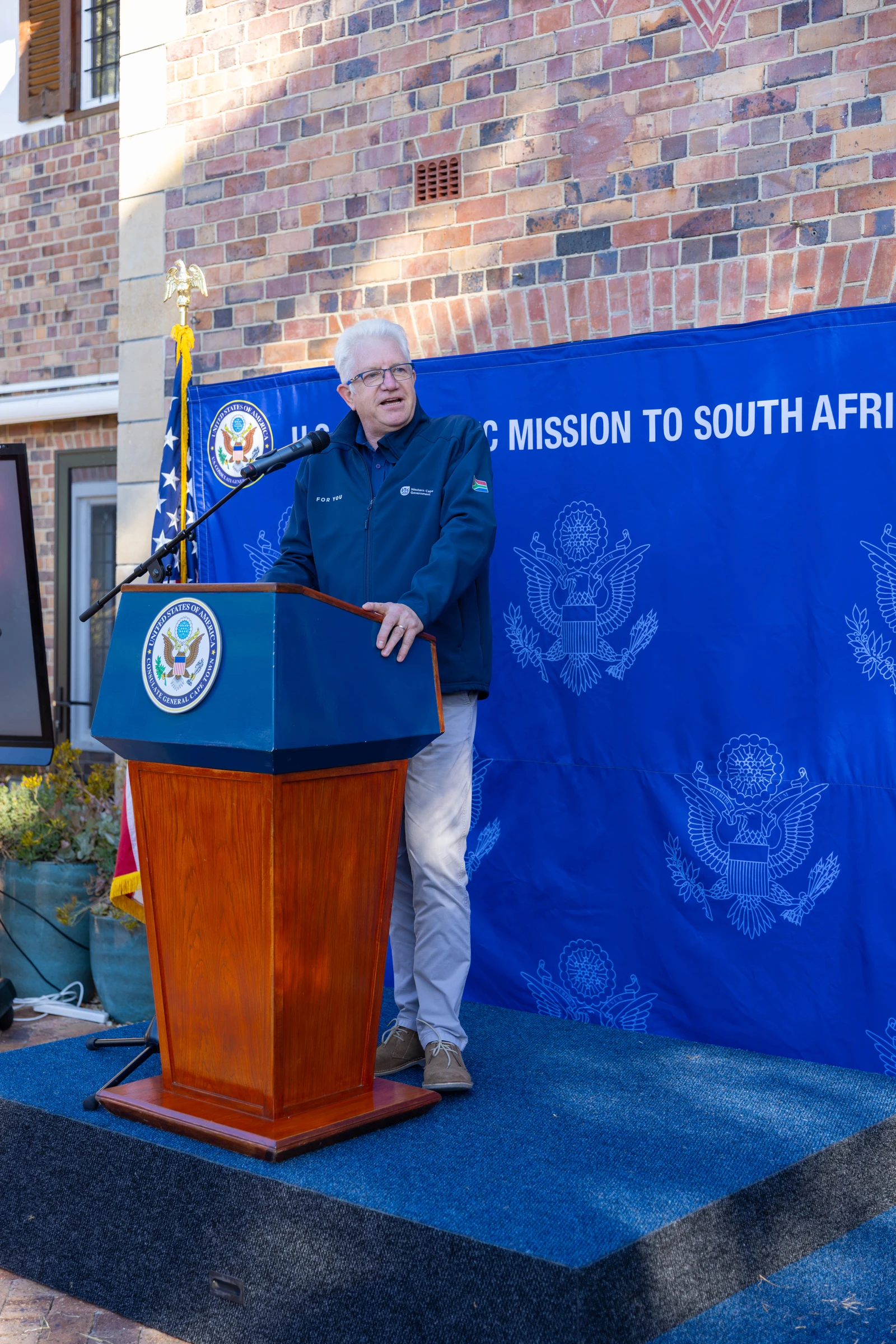 Western Cape Premier Alan Winde speaks at a podium outdoors.