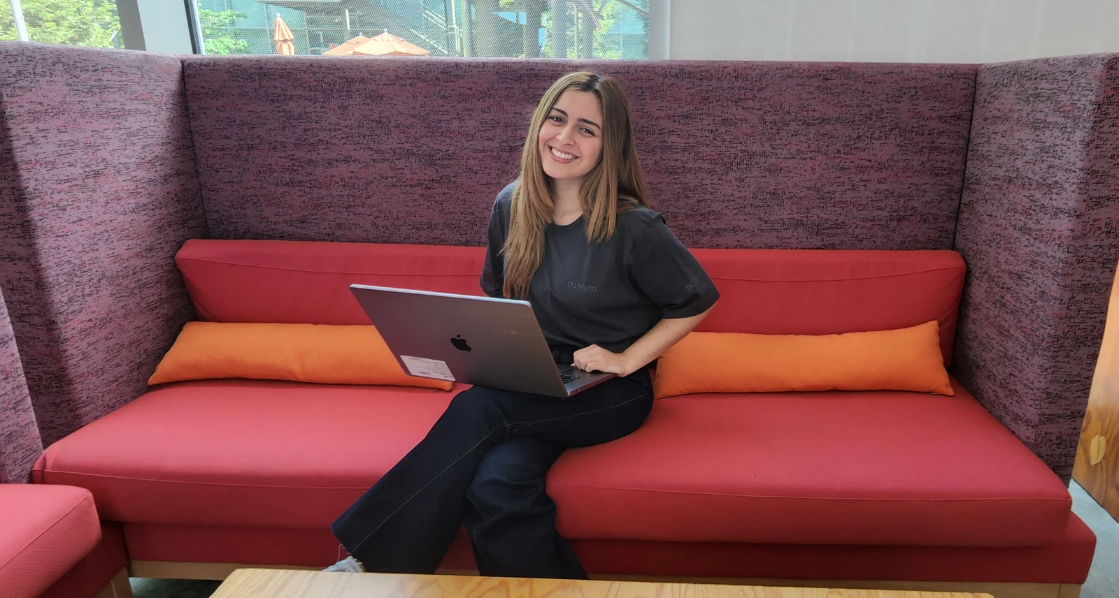Diana Vicezar, Meta Product Design, sits on a red sofa with a laptop.
