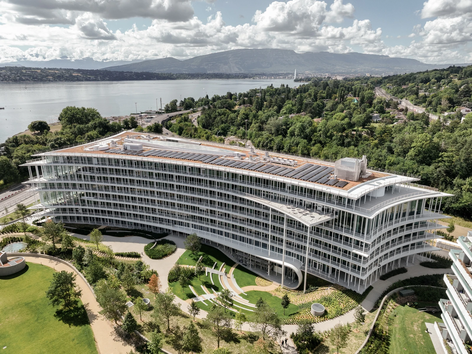 Aerial view of Lombard Odier headquarters building with a lake and mountains in the background.